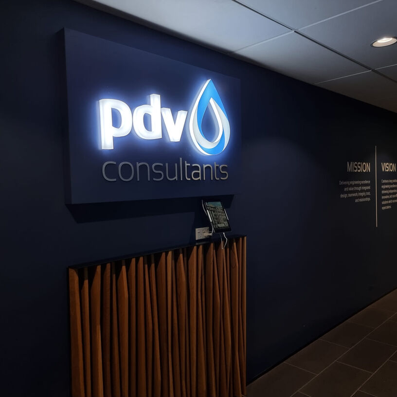 PDV Consultants illuminated sign in a reception area with mission and vision wall text