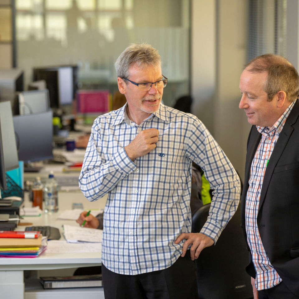 Experienced Professionals Two colleagues talking in an open-plan office